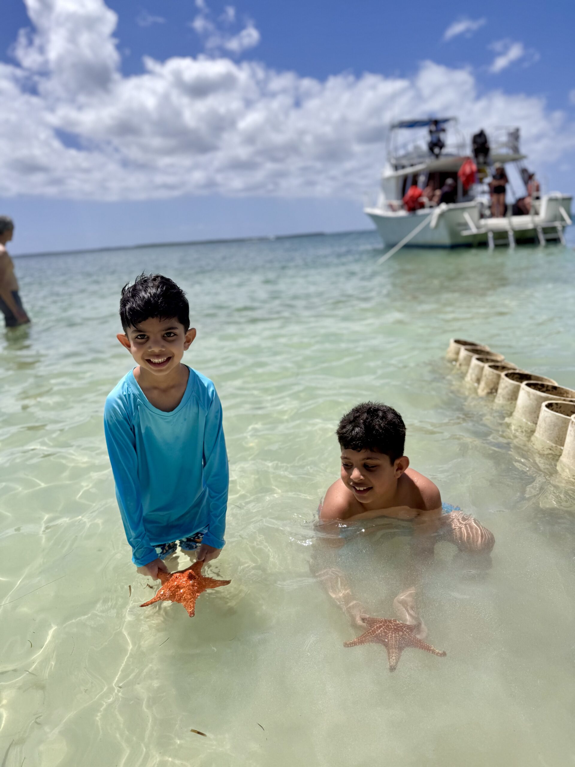 Kids holding starfish at Starfish Point in Grand Cayman